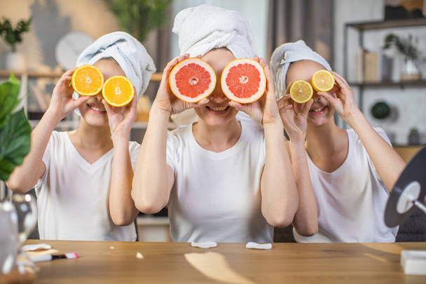 Mother with daughters keeping slices of citrus near eyes - Fotoğraf, Görsel