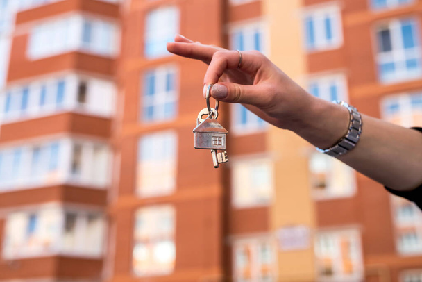 Satıcı evin arka planında anahtarları veriyor. satış veya kira kavramı - Fotoğraf, Görsel