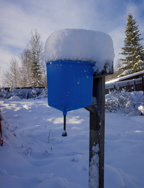 el lavabo azul en la calle de una casa de campo está cubierto de nieve desde arriba. la primera nieve cayó fuera de la ciudad. espacio de copia. - Foto, imagen