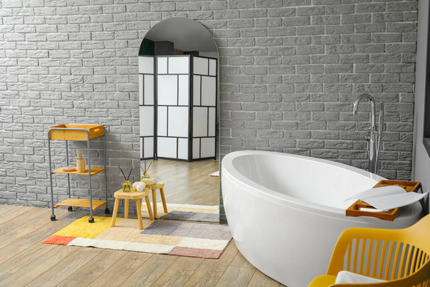 Miroir avec réflexion de l'écran pliant près du mur de briques dans la salle de bain - Photo, image