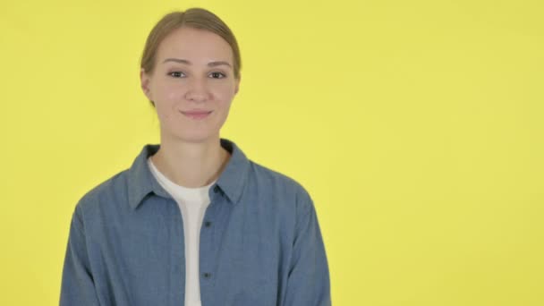 Nuori nainen osoittaa kohti tuotetta keltaisella taustalla  - Materiaali, video
