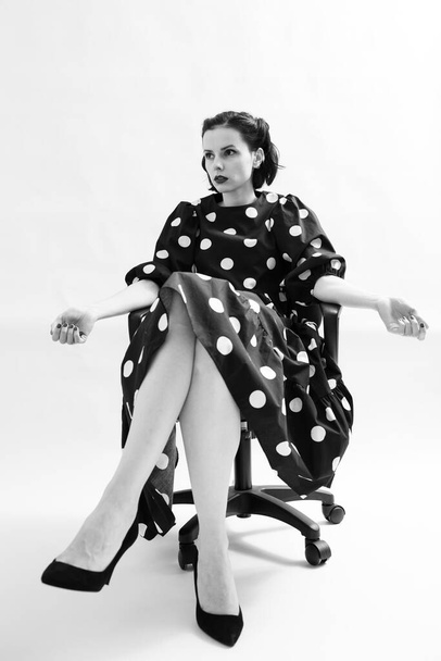 woman in polka dot dress sits on a chair - Fotoğraf, Görsel