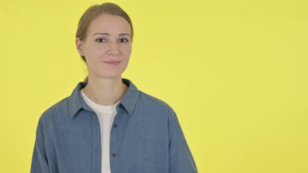 Νεαρή γυναίκα κρατώντας προϊόν στο χέρι σε κίτρινο φόντο  - Πλάνα, βίντεο