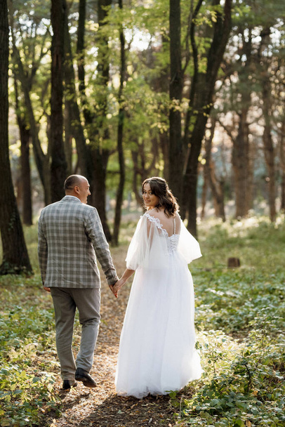 βόλτα της νύφης και του γαμπρού μέσα στο δάσος του φθινοπώρου τον Οκτώβριο - Φωτογραφία, εικόνα