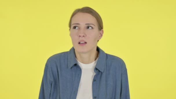 Młoda kobieta przestraszona, przerażona na żółtym tle  - Materiał filmowy, wideo