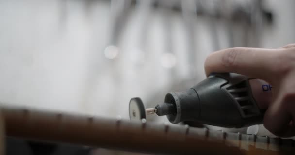 Luthier lucida nuovi tasti sulla tastiera della chitarra al negozio di riparazione di strumenti musicali, 4k 60fps Prores HQ - Filmati, video