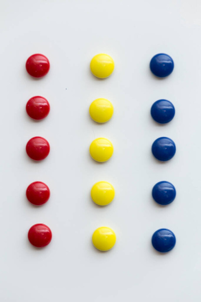 Red. yellow and blue. Round shaped colored magnets, on white background, placed as colored strips - Photo, image