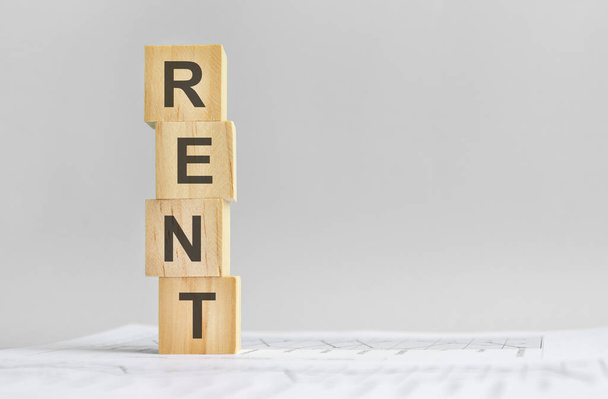 word Rent with wood building blocks, light gray background. document with numbers on background, business concept. space for text in left. front view - Photo, Image