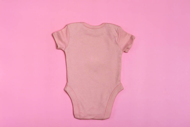 ベビーボディスーツのテンプレートのピンクの空白の裏側、ピンクの背景にクローズアップモックアップ。赤ちゃんの体のスーツ新生児のためのジャンプスーツ。上からの眺め - 写真・画像