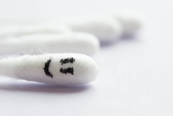 Close-up of cotton swabs with a smiling emoticon on a cotton swab in the foreground. Happiness concept - Foto, Imagen