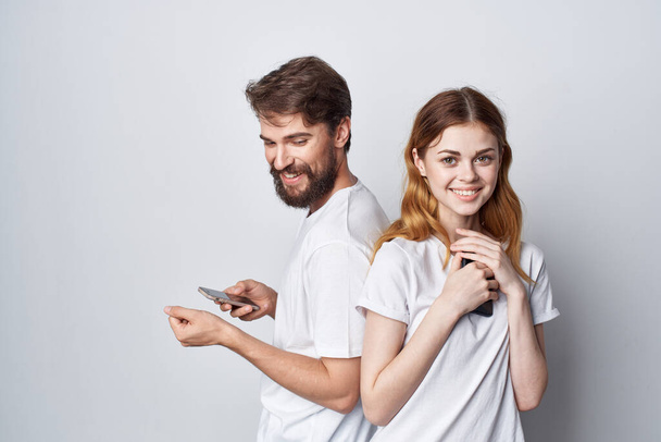 man and woman in white T-shirts with phones in their hands isolated background - Valokuva, kuva