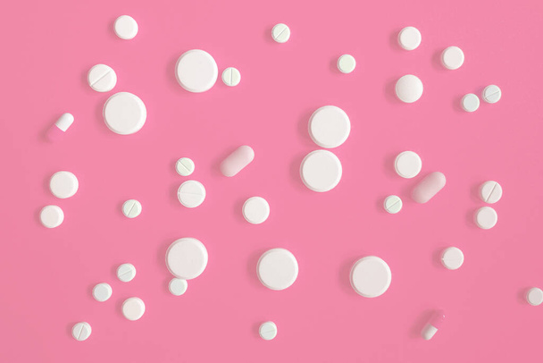 White medicines or pills on a pink background. Weight loss products, vitamins, hormones or sedatives. Women's health concept. - Фото, изображение