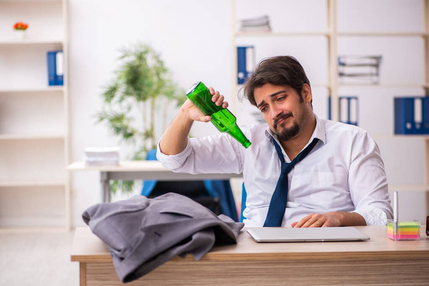 Молодой алкоголик, сидящий в офисе - Фото, изображение