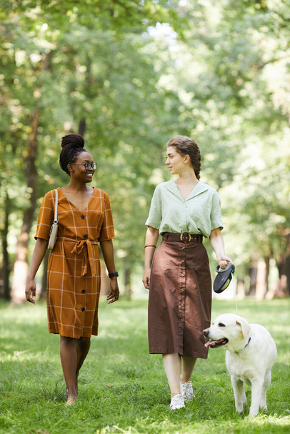 Twee jonge vrouwen wandelen met hond - Foto, afbeelding