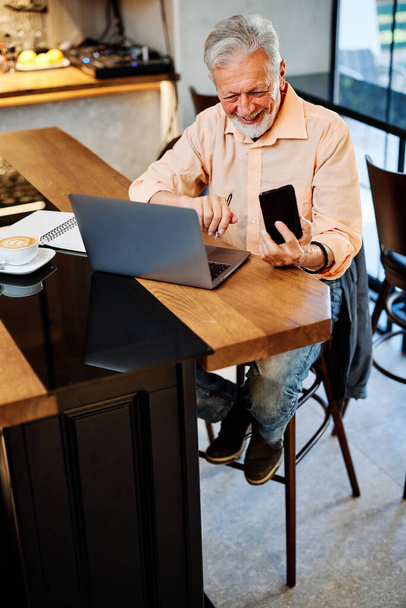 Un étudiant senior temporaire souriant assis dans un café et ayant un appel vidéo en pause. Étudiant senior au café. - Photo, image