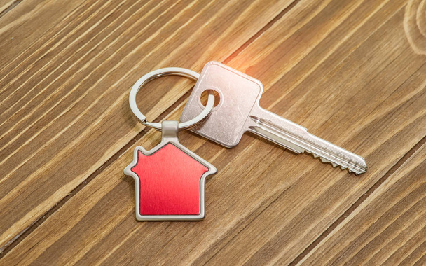 Schlüsselanhänger mit Haussymbol und Schlüsseln auf Holzgrund, Immobilienkonzept - Foto, Bild