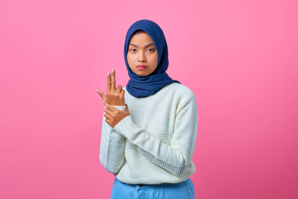 Portrét mladé asijské ženy držící symbolickou zbraň s gestem ruky - Fotografie, Obrázek