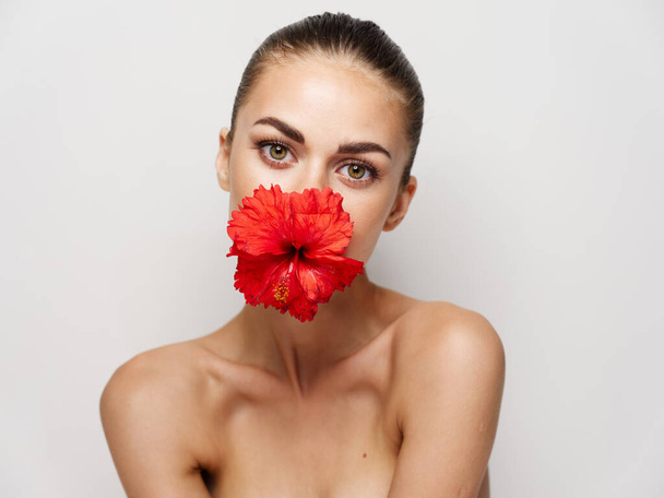 beautiful woman naked shoulders red flower charm cosmetics light background - Photo, Image