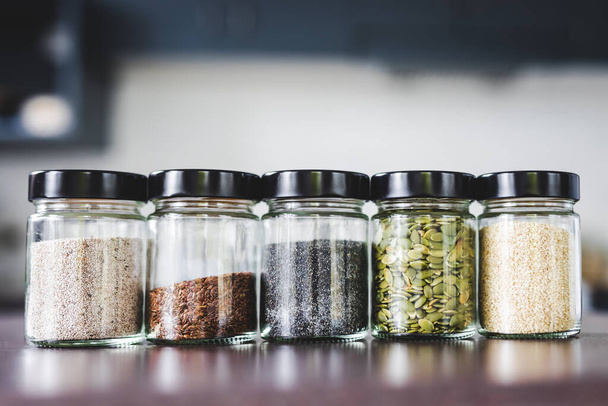 seeds including pumpkin chia sesame and flax in matching spice jars on kitchen counter, simple vegan ingredients and concept of flavoring your dishes - Fotografie, Obrázek