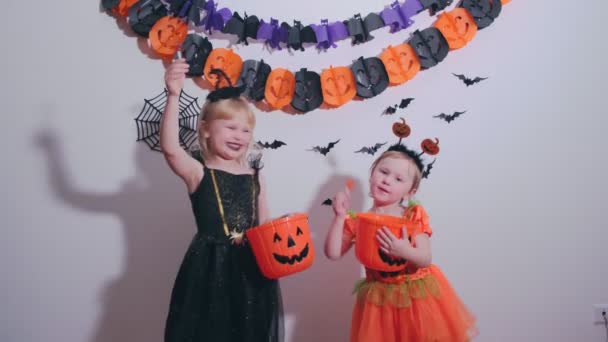 Pienet nätit tytöt Halloween-asussa syövät tikkareita kotona Hallowen-juhlissa.. - Materiaali, video