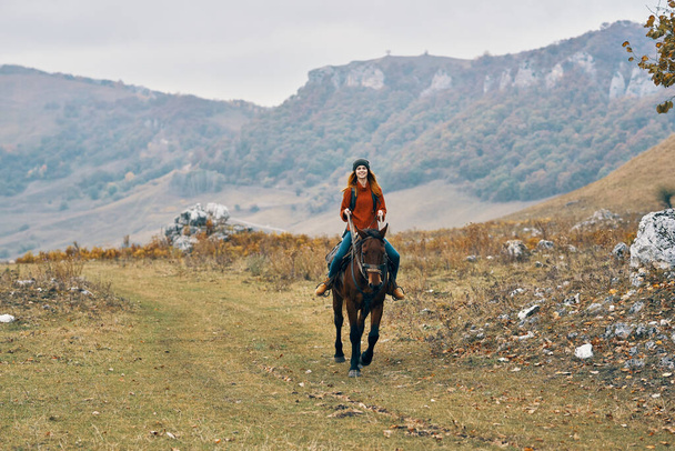 woman hiker riding a horse on nature travel - Foto, afbeelding