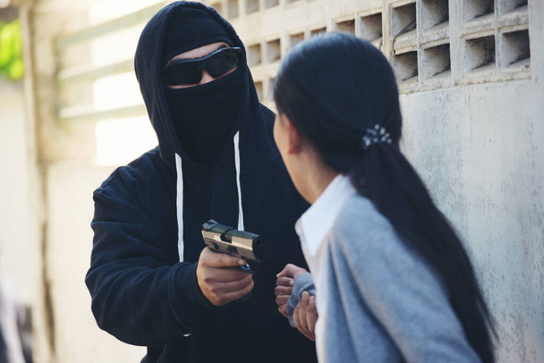 Thief armed man rob woman by gun on street so scared shocked face. Frightened asian woman was rob aggressive by danger bandit man. Robbery thief using gun burglar. Criminal aggression crime concept. - Foto, imagen