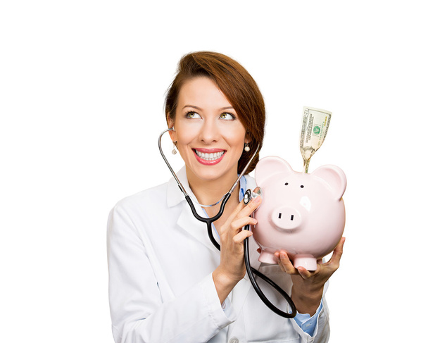 Doctor, nurse listening with stethoscope to piggy bank - Photo, Image