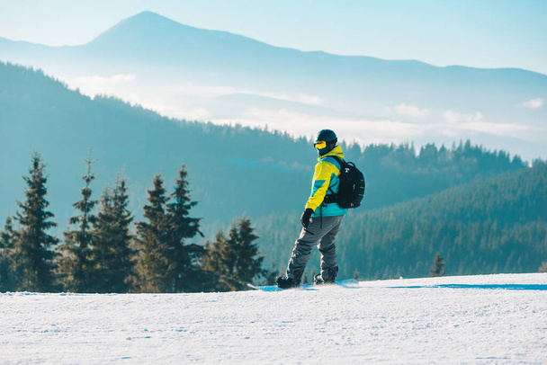 homme marchant par colline avec des montagnes de snowboard sur fond - Photo, image