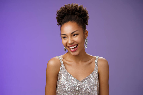 Nahaufnahme redselig elegant Glamour afrikanisch-amerikanische junge Mädchen Host Party tragen luxuriöse modische silberne Kleid reden glücklich lachen während des Gesprächs stehend blauer Hintergrund - Foto, Bild