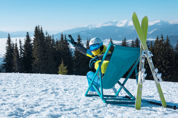 nő síelő ül a székben, gyönyörű hegyekkel panorámás kilátás síközpont. téli vakáció - Fotó, kép