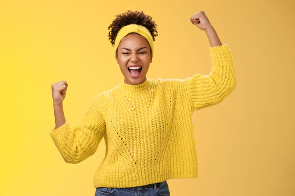 Active outgoing confident cheerful african-american female fan place bet hopefully yelling encourage team win standing raised fists victory celebrating gesture shouting proudly, yellow background - Photo, Image