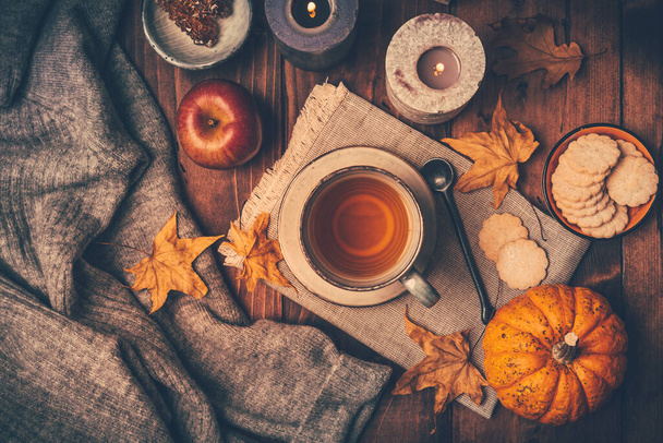 Warme thee met koekjes, appel- en herfstbladeren en pompoenen op houten ondergrond - Foto, afbeelding