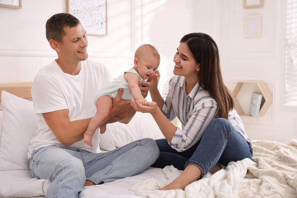 Happy family with their cute baby on bed at home - Photo, Image