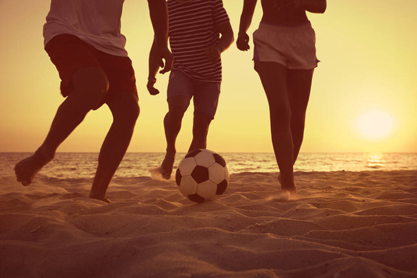 Friends playing football on beach at sunset, closeup - Foto, Imagen