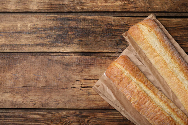 Fresh tasty baguettes on wooden table, flat lay. Space for text - Foto, Imagem