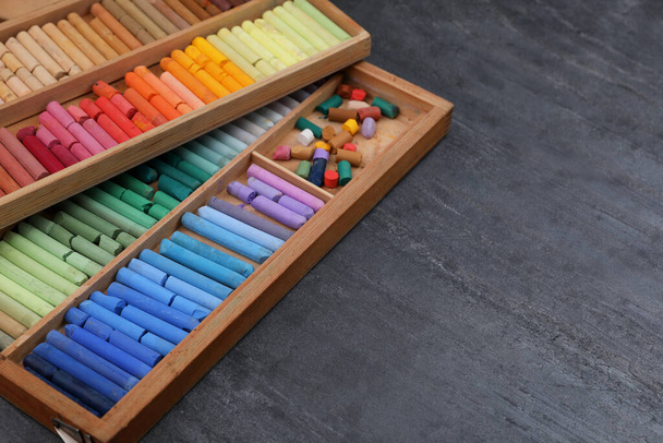 Colorful pastels in wooden trays on grey stone table, space for text. Drawing materials - Foto, Bild
