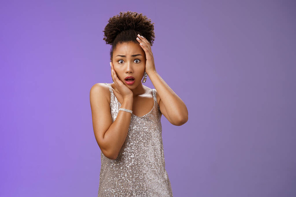 Shocked afraid timid insecure african-american woman in silver trendy dress panic widen eyes frightened look camera touch head terrified anxiously staring gasping speechless shook, blue background - Photo, Image