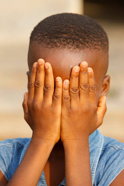 Shy African boy hiding his face in hands.  Togo. - Foto, afbeelding