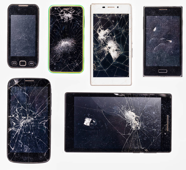Screens of electronic devices shattered when hit by a heavy tool. Damaged LCD screens. Isolated background.  - Foto, Bild