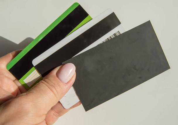 Το χέρι μιας γυναίκας που κρατά μια άδεια μαύρη κάρτα με ένα αντίγραφο του χώρου και πολλές πλαστικές τραπεζικές κάρτες, η έννοια της χρηματοδότησης και των δαπανών. - Φωτογραφία, εικόνα