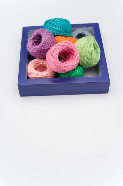 multicolored decorative yarn balls in a wooden box on a white surface - Fotoğraf, Görsel