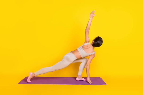 Photo of flexible anonymous trainer lady do exercise raise arm wear cropped top isolated yellow color background - Foto, afbeelding