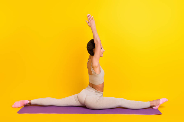 Photo of flexible anonymous trainer lady do exercise raise arm wear cropped top isolated yellow color background - Fotografie, Obrázek