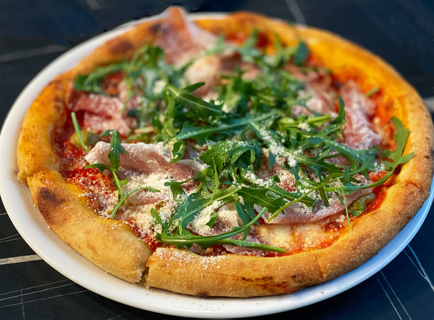 Gros plan sur une pizza de table restaurant au prosciutto, roquette et parmesan - Photo, image