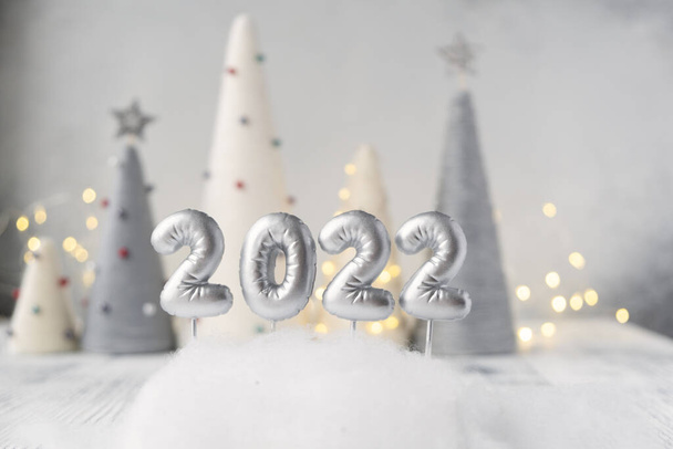 Christmas greeting card with silver number 2022. Yarn wrapped xmas cone trees and garland on background - Fotoğraf, Görsel