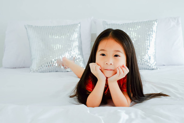 Portret piękny słodkie azjatyckie dziecko dziewczyna sobie czerwony mandarynka suknia lub sukienka cheongsam na łóżku, świętować chiński nowy rok koncepcja - Zdjęcie, obraz