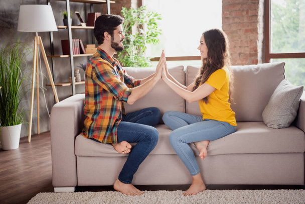 Photo of beautiful charming young lovers dressed casual clothes sitting sofa smiling holding arms indoors loft apartment - Φωτογραφία, εικόνα
