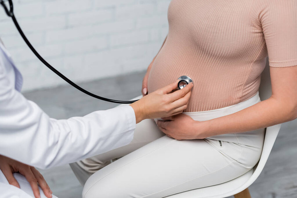 vista parziale della donna incinta vicino al medico che esamina la pancia con stetoscopio - Foto, immagini