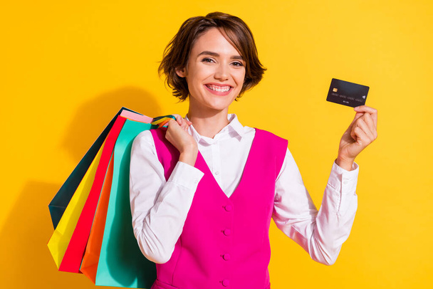 Portrait of attractive cheerful girl holding bags bank card order new clothes gifts isolated over bright yellow color background - Фото, зображення