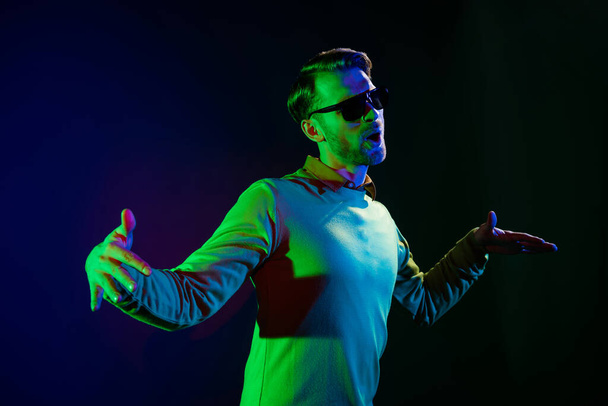 Photo portrait of man wearing sunglass enjoying music party in night club isolated dark color background - Φωτογραφία, εικόνα